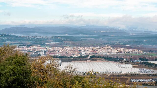 Time lapse shot of Tordera from Castell de Palafolls, Spain. Cloudy day with misty mountains in the background.