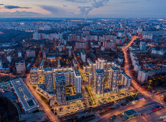 Modern houses with backlight on the background of the night city, in the frame high-rise buildings and old buildings, aerial photography