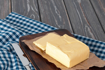 Wooden board with butter on blue checkered napkin