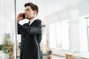 Image of concentrated businessman talking on cellphone while working