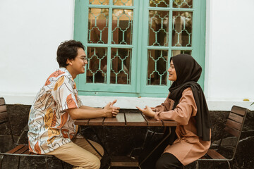 young couple laughing while chatting face to face in a coffee shop