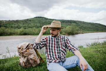 Portrait of a handsome young bearded hipster man in a straw hat outdoors