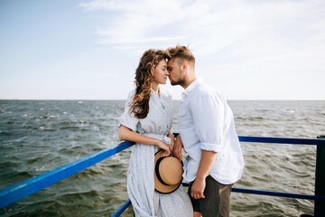 A young man kisses his girlfriend on the sea pier. The concept of summer love