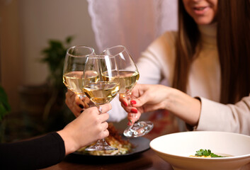 female friends - hands clinking white wine glasses, restaurant or bar on background, close up view. evening, celebration and holidays concept