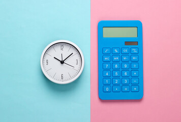 White clock and calculator on blue pink background. Minimalistic studio shot. Top view