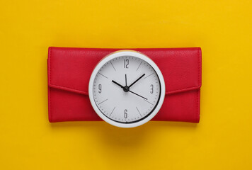 Time to make money. White clock and wallet on yellow background. Minimalistic studio shot. Top view
