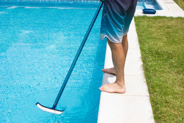 Cleaner of the swimming pool . Man in a blue shirt with cleaning equipment for swimming pools, sunny day