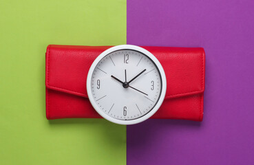 Time to make money. White clock and red wallet on green purple background. Minimalistic studio shot. Top view