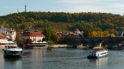 Fototapeta na wymiar Pleasure boats on the Vltava in the fall. Petrin hill in the fall.