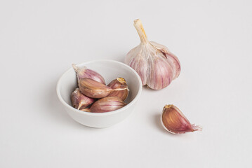 Whole head and cloves of purple garlic on a white background