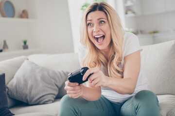 Photo of beautiful cheerful funny lady sit comfy couch positive emotions play video games stay home quarantine excited addicted gamer scream worried winner living room indoors
