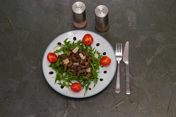 Tasty and juicy grilled meat arugula, cheese, tomato sauce and spices on a dark gray concrete background, top view