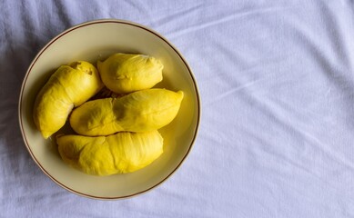 Durian fruit peeled in a dish on white background.