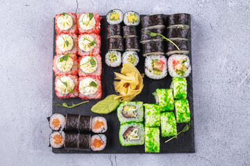 Sushi Set sashimi and sushi rolls served on stone slate