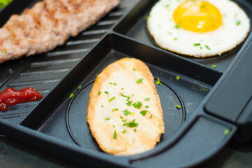 Lunch, grilled steak or cutlet, toast and egg on a black plate. The concept of healthy diet, diet, menu. Place for text with left, copy space.