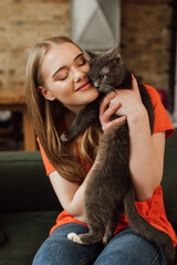 cheerful girl with closed eyes holding in arms fluffy cat