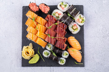 Sushi Set sashimi and sushi rolls served on stone slate