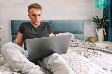 Distance learning online-education and work. Male programmer working office working remotely from home on a bed