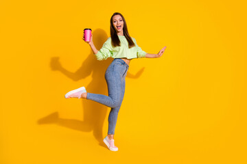Fototapeta na wymiar Full length photo of cheerful funny girl enjoy free time weekend hold take-away beverage mug wear good look clothes sneakers isolated over bright color background