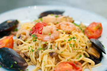 Spaghetti pasta with shrimp, mussels, tomatoes and cheese, close-up, side view. Tasty, traditional food Italians