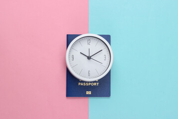 Time to travel. Passport and clock on a pink blue pastel background. Top view
