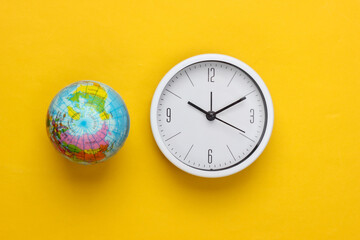 Clock and globe on a yellow background. World time. Top view