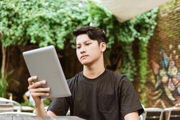 Serious young man using a tablet pc for work outdoor