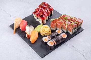 Sushi Set sashimi and sushi rolls served on stone slate