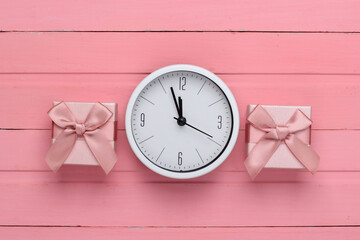 Gift boxes with clock on pink wooden background. Top view