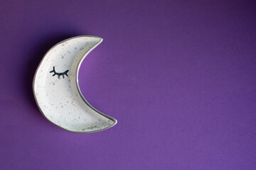 Fototapeta na wymiar moon shaped plate on purple background