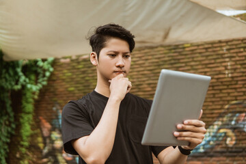 Serious young man using a tablet pc for work outdoor