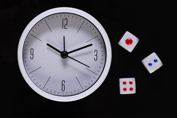 Good luck time. White clock with dice isolated on black background. Top view.