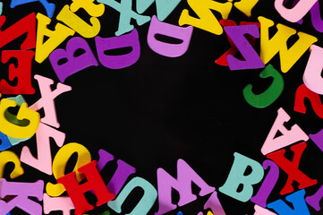 Many colored wooden letters with copy space isolated on black background.