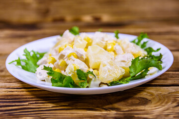 Festive salad with chicken breast, canned pineapple, cheese, sweet corn and mayonnaise on wooden table