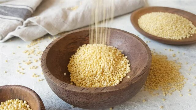Raw dry hulled millet in a bowl with a spoon