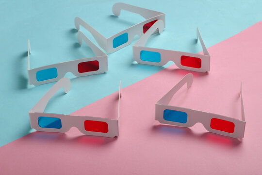 Many stereoscopic anaglyph disposable paper 3d glasses on pink blue pastel background.