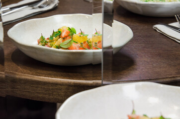 Healthy eating concept. Fresh fruit salad with strawberry, passion fruit, kiwi, peach, leaf, and micro greens with a glass of clean water on a table in a restaurant.