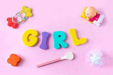 Word girl of colorful letters, baby accessories and toys on pink background. Flat lay, top view.