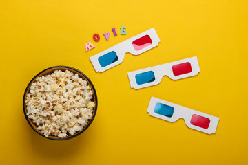 Movie time. Stereoscopic anaglyph disposable paper 3d glasses and popcorn bowl on yellow...