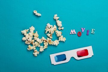 Movie time. Stereoscopic anaglyph disposable paper 3d glasses with popcorn on blue background. Top...