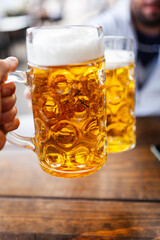 Friends drinking cold beer and clinking glasses  at an open air restaurant