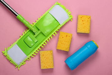 Cleaning products. Plastic green mop, sponges, bottle of detergent on pink background. Disinfection and cleaning in the house. Top view