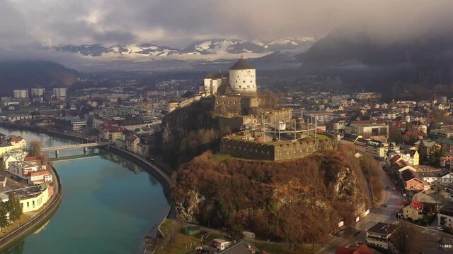 Aerial view of mountain town Kufstein with medieval hilltop fortress, dramatic winter scenery at sunrise, river Inn meandering through the valley - Austrian Alps from above, Tyrol, Austria, Europe