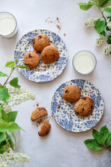 Flat lay shot of chocolate chip cookies with milk and some green blooming branches