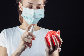 Woman in a median face mask holding model strain virus and disinfects with antiseptic on a black...