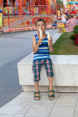 Cute boy eating ice cream on a summer street background
