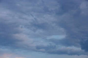 Beautiful dramatic gray and white clouds on blue sky, variety of shapes, silhouettes and shades at sunset time