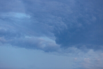 Beautiful dramatic gray and white clouds on blue sky, variety of shapes, silhouettes and shades at sunset time