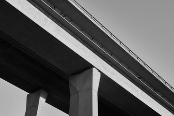 Section of a motorway bridge with two pillars as black and white photography. The bridge runs...