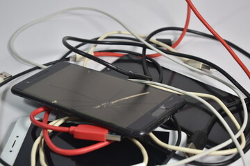 Closeup of old broken mobile phones with charging Cables and USB cables wires E-waste pollution 